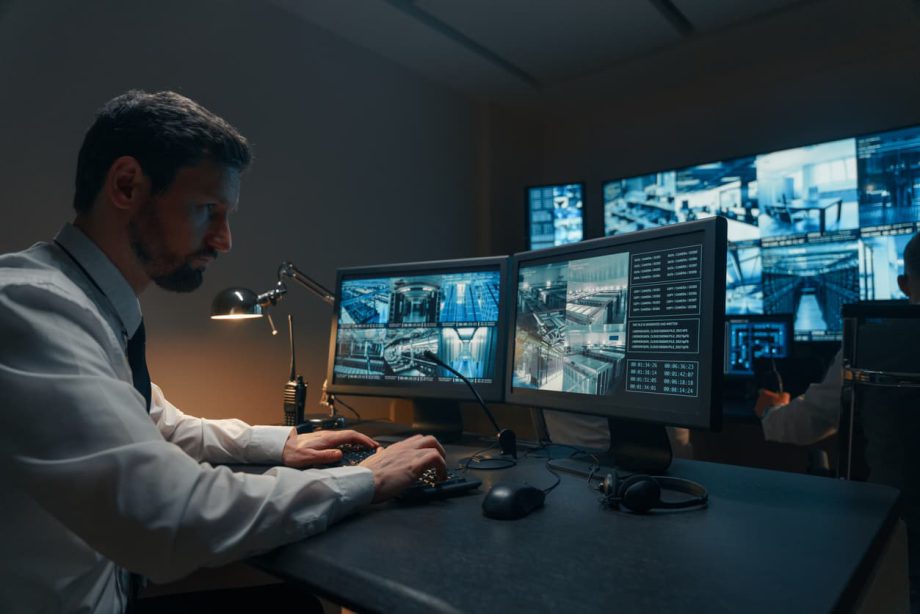 A security guard following home security trends by monitoring a video feed