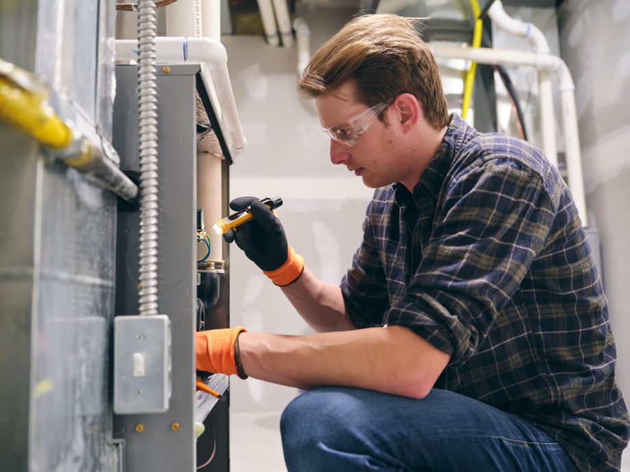 A property maintenance worker repairs a furnace