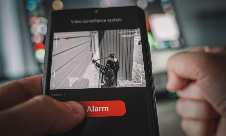 A resident checking a smartphone alert from his high-end security system.