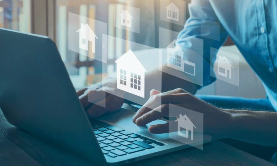 Hands typing on a laptop keyboard with images of houses superimposed of them.