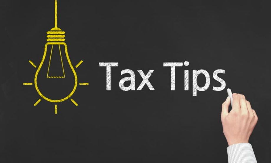 A hand writing “tax tips” on a chalkboard.