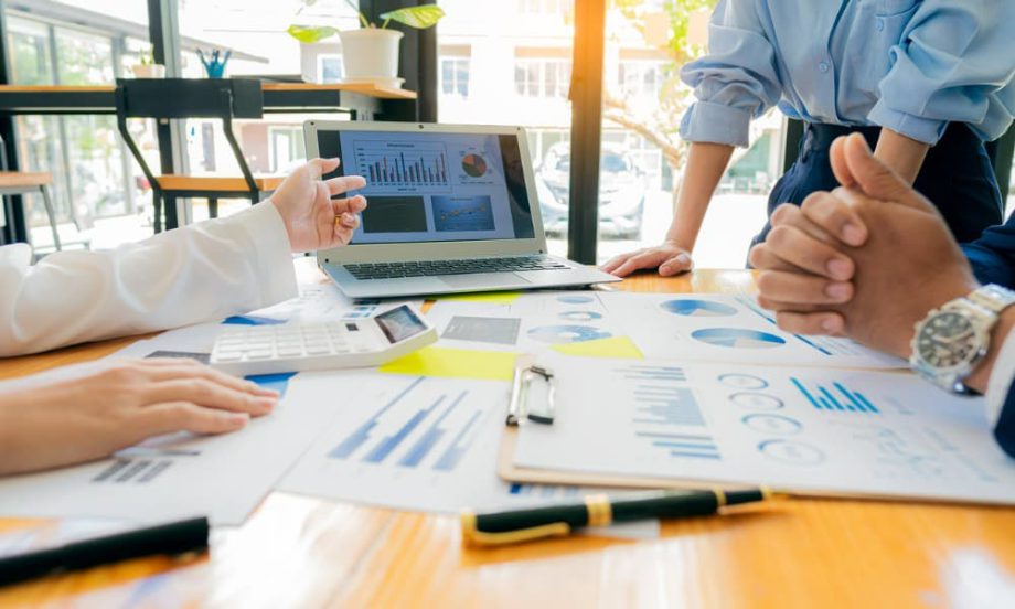 A group of people sitting around a conference table looking at charts.